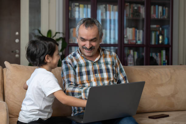 istock Cute little boy with his father using laptop in living room 2204600617