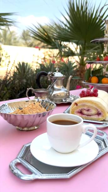 istock Cup positioned next to cake roll with creamy layers, berry toppings and polished silver tray highlighting refined cake presentation. Cup adds elegance to classic cake display. Vintage dessert concept. 2204603091