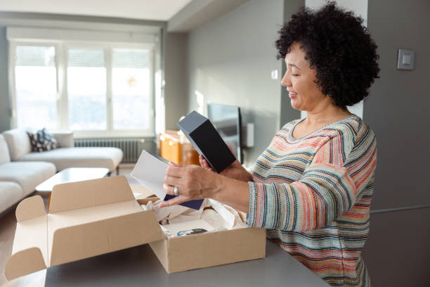 istock Woman smiling while unboxing a delivery package in a bright modern home 2204610720