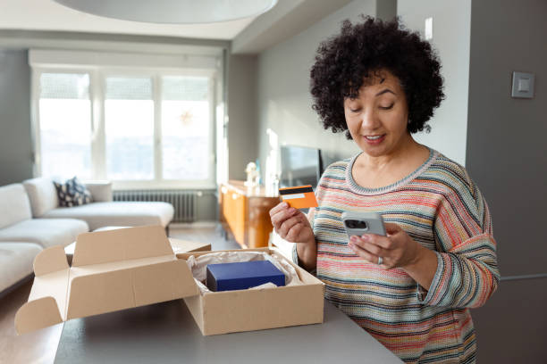 istock Woman shopping online with a smartphone while unboxing a delivery package 2204610853