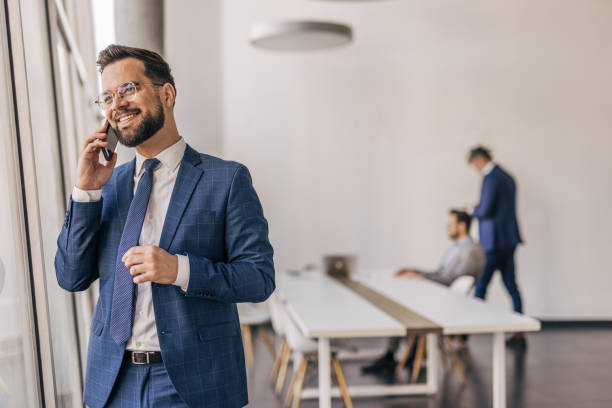 istock Smiling businessman talking on phone in modern office 2204611046