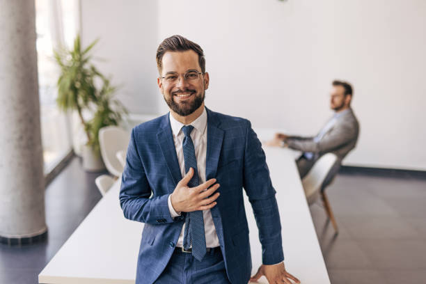 istock Smiling businessman gesturing appreciation in modern office 2204611245