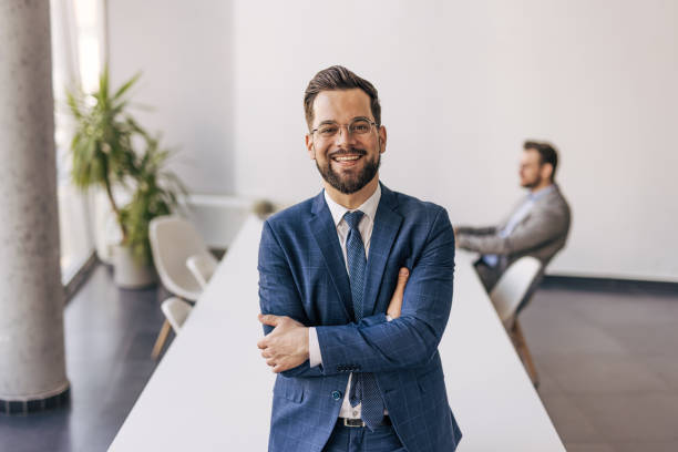 istock Smiling businessman standing with arms crossed in modern office 2204611268