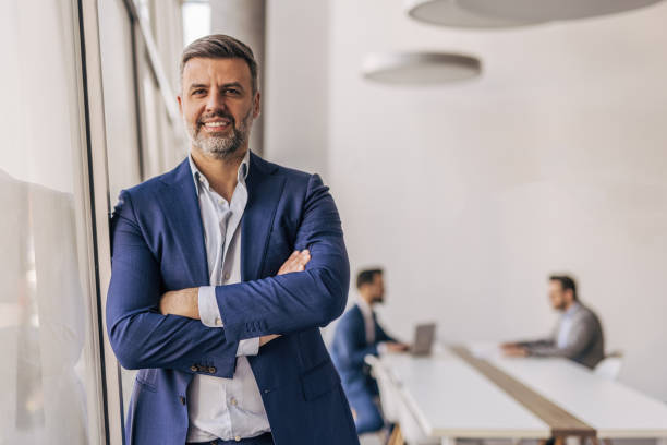 istock Confident businessman smiling with folded arms in modern office 2204611445