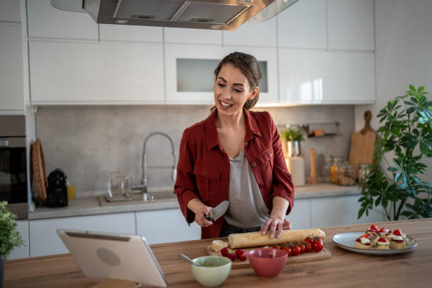 istock Woman making lunch while having a video call in a modern kitchen 2204611486