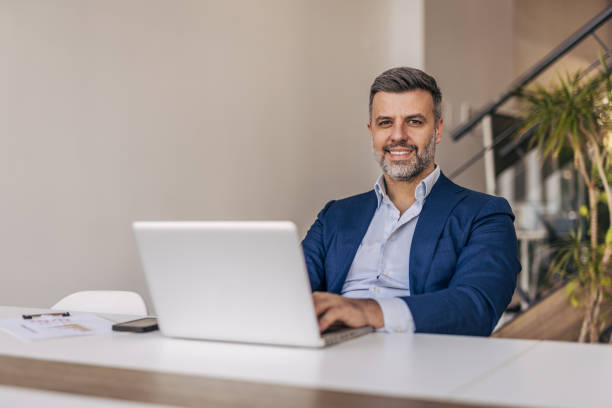 istock Confident businessman working on laptop in modern office 2204612120
