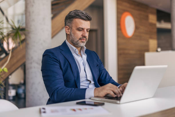 istock Focused businessman working on laptop in modern office 2204612155