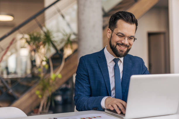istock Young businessman working on laptop in modern office, smiling 2204612305