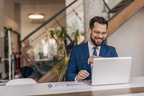 istock Smiling businessman working on laptop in modern office 2204612361