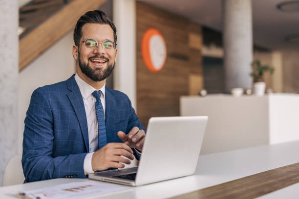 istock Smiling businessman working on laptop in modern office 2204612366