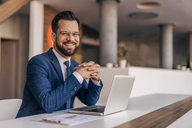 istock Businessman smiling looking at camera working on laptop in office 2204612887