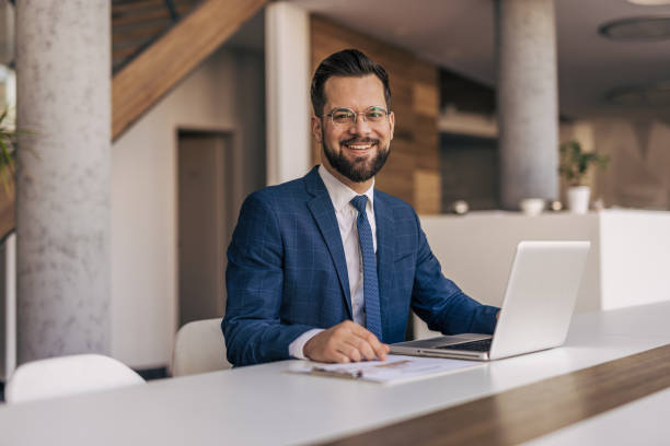 istock Smiling businessman working on laptop in modern office 2204612971