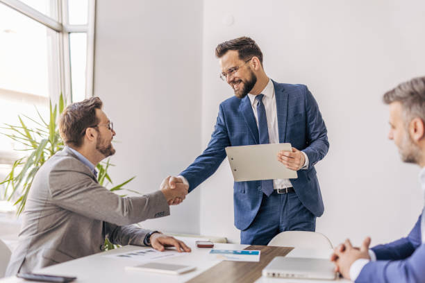 istock Businessmen shaking hands after successful meeting in office 2204615031