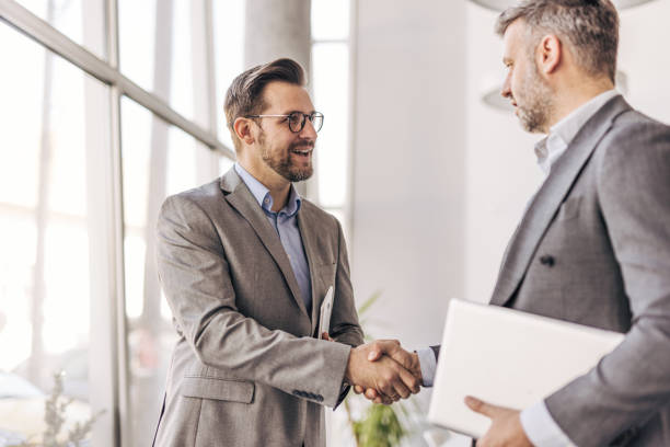 istock Two businessmen shaking hands in modern office 2204615827