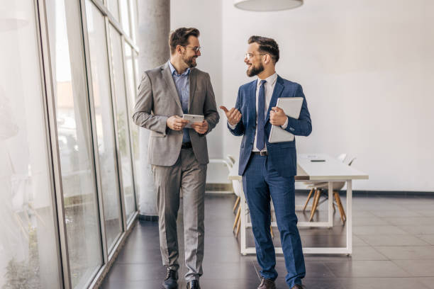 istock Two businessmen walking and talking in modern office 2204615974