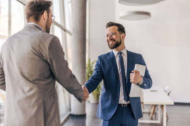 istock Two businessmen shaking hands in modern office 2204616135
