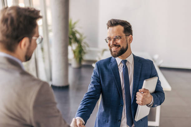 istock Two businessmen shaking hands in modern office 2204616136