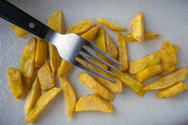Potato wedges and fork left on dinner plate. Nobody.