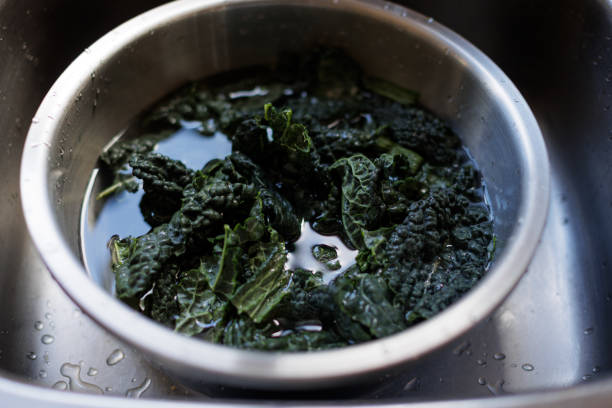 Close view of kale leaves in a bowl being washed in the kitchen sink