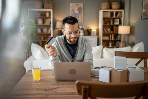 istock Young man making online purchases using credit card at home 2204622050