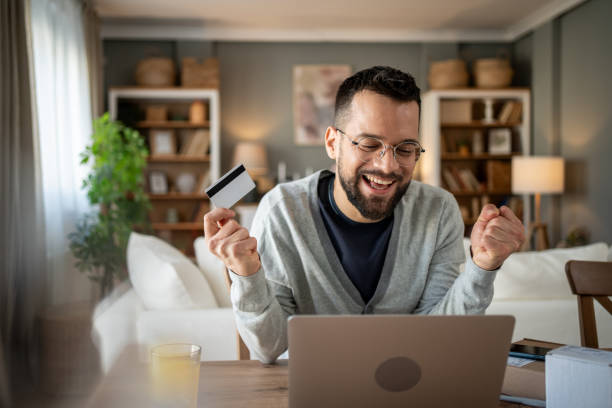 istock Happy man making online payment with credit card at home 2204622063