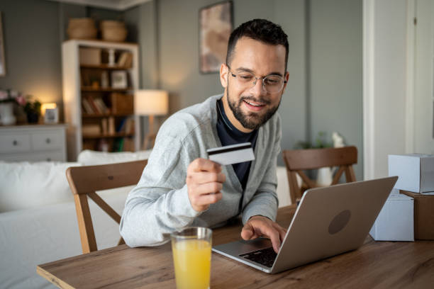 istock Young man making online payment using credit card at home 2204622064