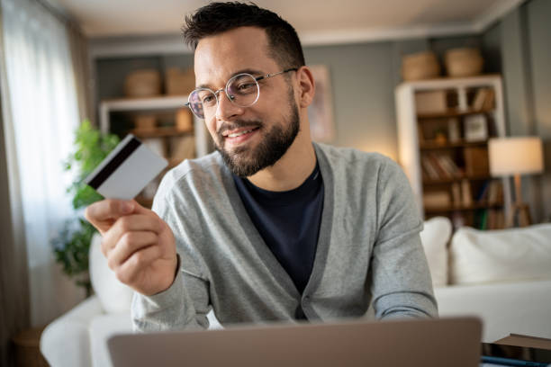 istock Young man making online payment using credit card and laptop at home 2204622072