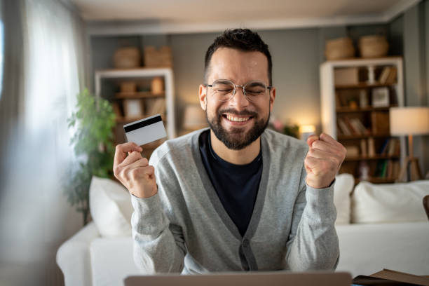 istock Excited man making online payment with credit card at home 2204622081