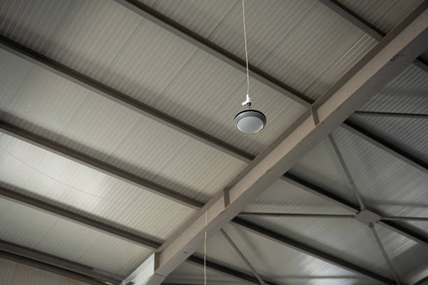Looking up to an industrial ceiling with metal air duct and pendant light
