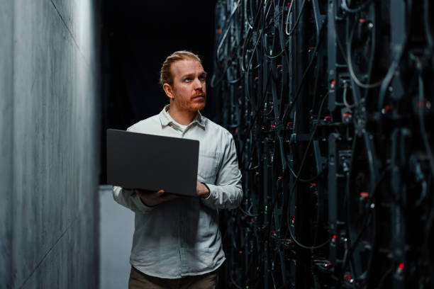 istock IT specialist holding laptop and checking server hardware in data center 2204625631