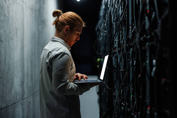 istock IT specialist working on a laptop in a server room 2204625636