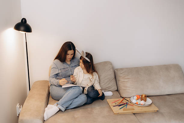 istock Mother and Daughter Engaged in Creative Activity on Comfortable Couch 2204637889