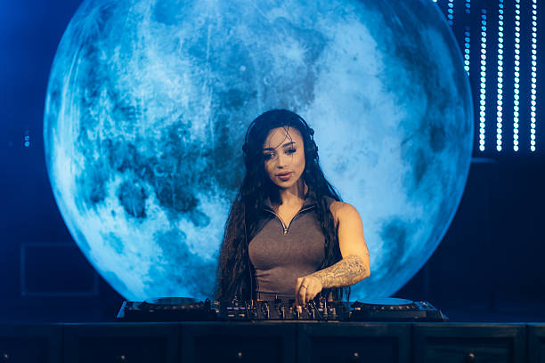 istock Female DJ Performing in Front of an Illuminated Moon Backdrop and DJ Console 2204637935