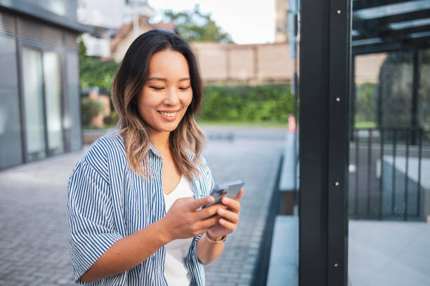 istock Asian woman using smartphone outdoors in urban environment 2204640008