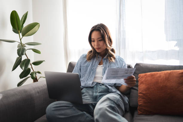 istock Young woman managing finances with laptop and paperwork 2204640023