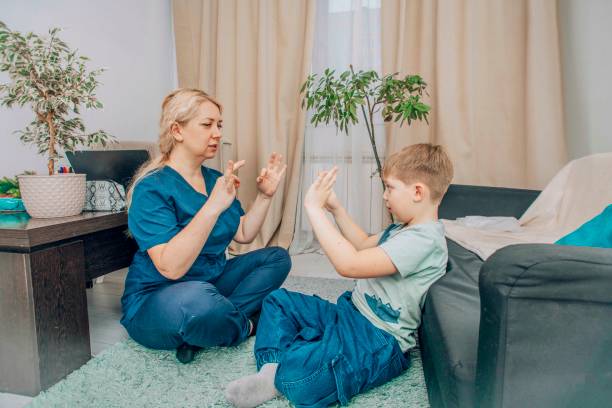 istock female therapist and boy practicing hand gestures in therapy session, cozy home setting, concept of child development and alternative communication 2204648092