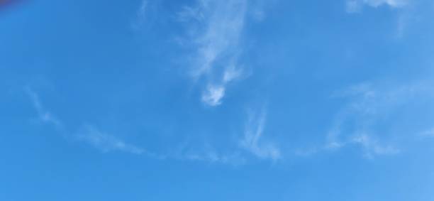 istock The lightness of the blue sky is enhanced by thin, scattered clouds that resemble delicate white strokes in the celestial vastness. The contrast between the deep blue and the soft clouds creates an atmosphere of peace and visual balance. 2204648661