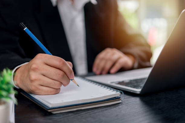istock man hands with pen writing on notebook in the office.learning, education and work.writes goals, plans, make to do and wish list on desk. 2204651678