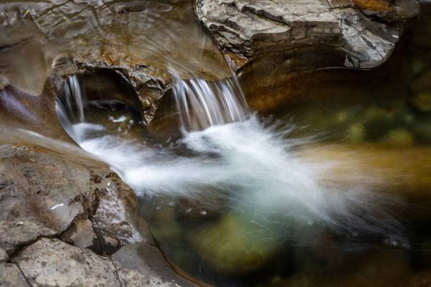 istock Serene waterfall cascading over rocks into a clear pool. 2204652799
