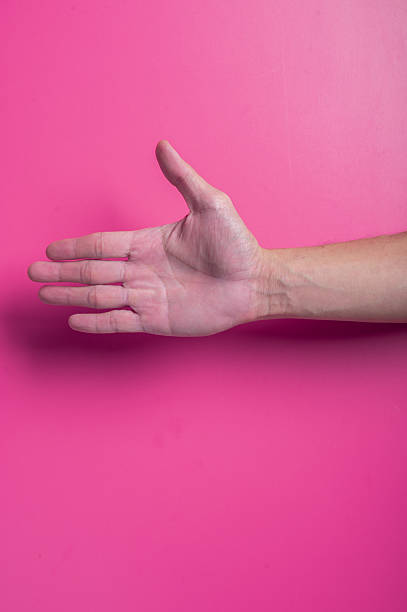 istock Outstretched human hand with fingers extended in a reaching gesture, captured against a pink background, symbolizing connection, help, or request in a clear, expressive and minimal layout. 2204657489