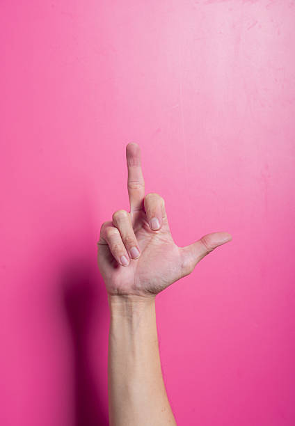 istock Asian hand showing a raised middle finger in a direct offensive gesture, centered against a pink background, symbolizing anger, protest, or rebellion with a bold and provocative expression. 2204657527