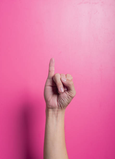 istock Asian hand raising one index finger upward while others remain curled, isolated against a bright pink background, commonly used to indicate attention, number one, or to emphasize a point. 2204657737