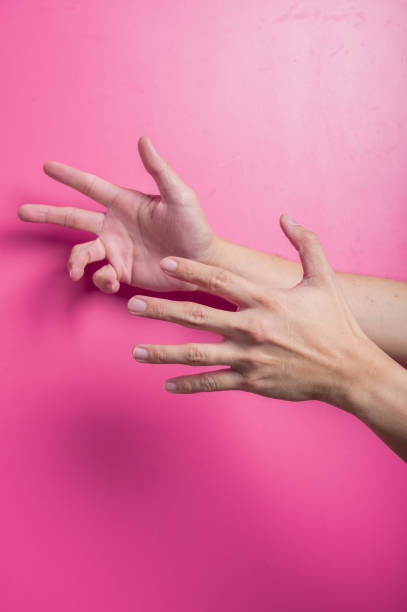 istock Two Asian hands interacting in a dynamic pose, one gripping the other's wrist and fingers extended, suggesting control, assistance, or struggle, against a vivid pink background with dramatic lighting. 2204657848