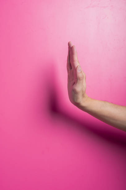 istock Asian hand with open palm held vertically, resembling a stop or halt gesture, positioned against a solid pink background, representing caution, refusal, boundaries, or assertive communication. 2204657849