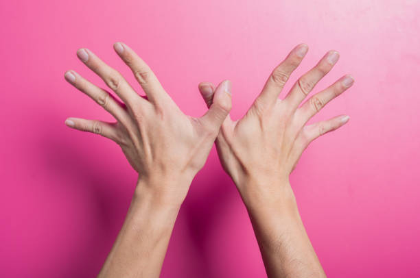 istock Two Asian hands spread wide with thumbs joined, forming a butterfly-like shape against a bright pink background, representing freedom, imagination, creativity, or expressive hand art and symbolism. 2204657913