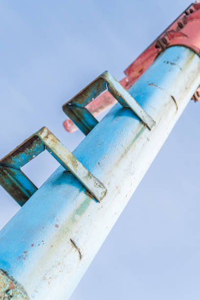 A close-up shot of an old blue metal pole with rusted ladder rungs leading up to a red structure. The worn paint and corroded metal indicate exposure to the elements over time. This pole was likely part of an industrial or recreational infrastructure, such as a ski lift or utility structure.