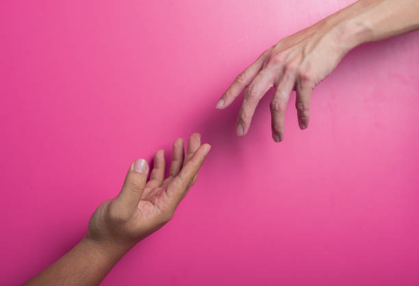 istock Two Asian hands reaching toward each other against a bright pink background, symbolizing connection, support, or human touch. Clean composition emphasizes emotion and interpersonal interaction. 2204658945
