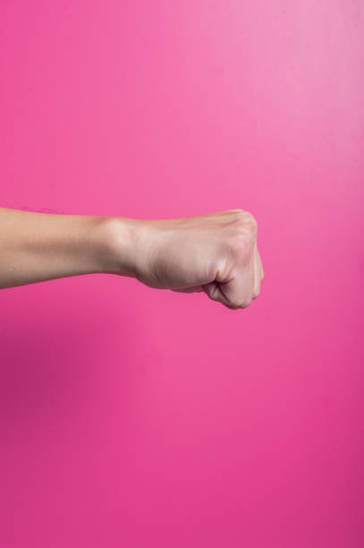 istock Asian hand showing raised clenched fist on pink background, symbolizing power, resistance, strength, protest, or motivation in a bold and impactful visual expression. 2204659727
