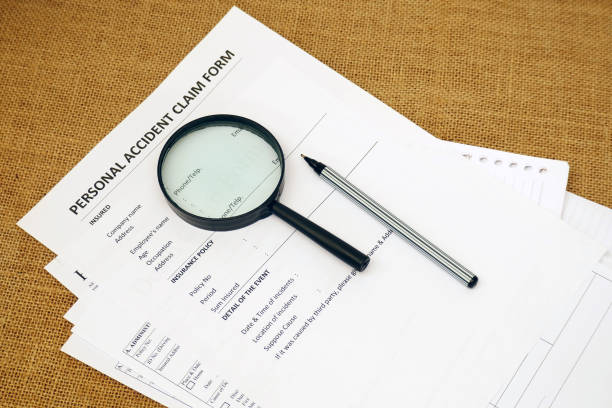 Personal accident claim form, magnifying glass, pen, and paperwork visible