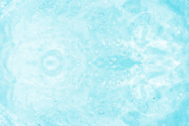 Blue water with ripples on the surface. Defocus blurred transparent blue colored clear calm water surface texture with splashes and bubbles. Water waves with shining pattern texture background.